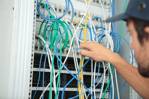 telecom technician plugging in ethernet cables cable management