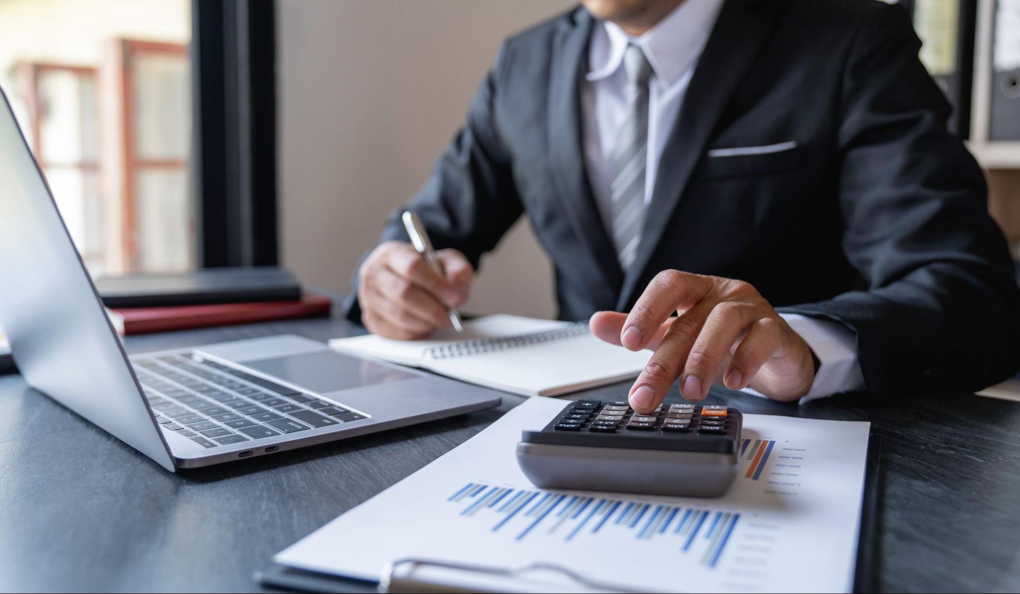 A businessman using a calculator at the desk