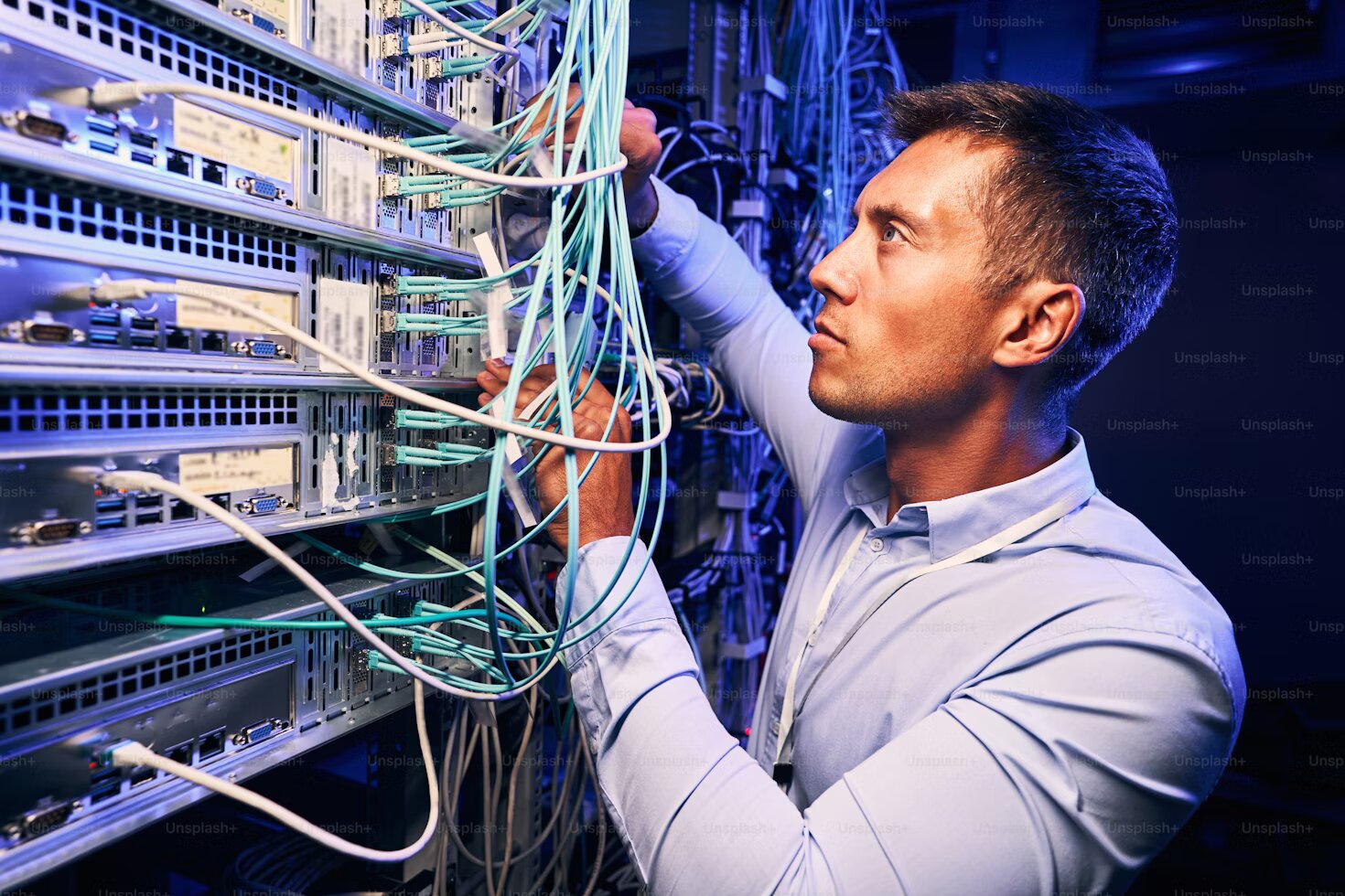 A man working connecting cables to ports.