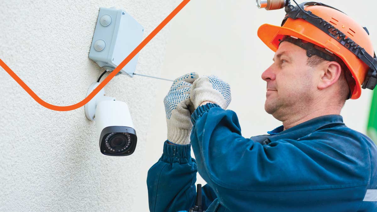 Man wearing helmet installing security camera on building