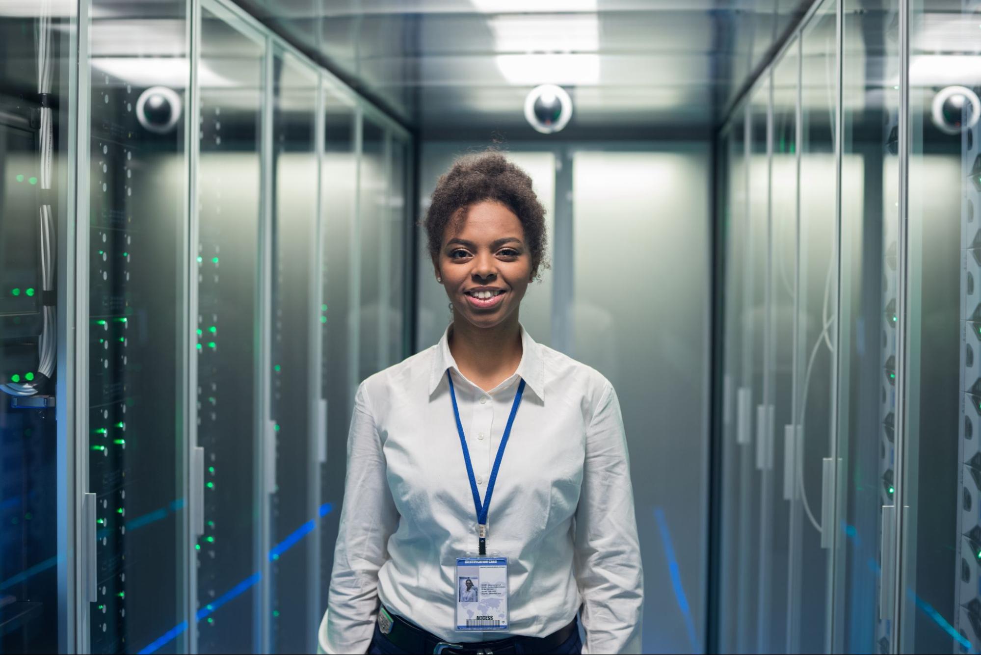 Woman in white shirt facing camera standing in server room