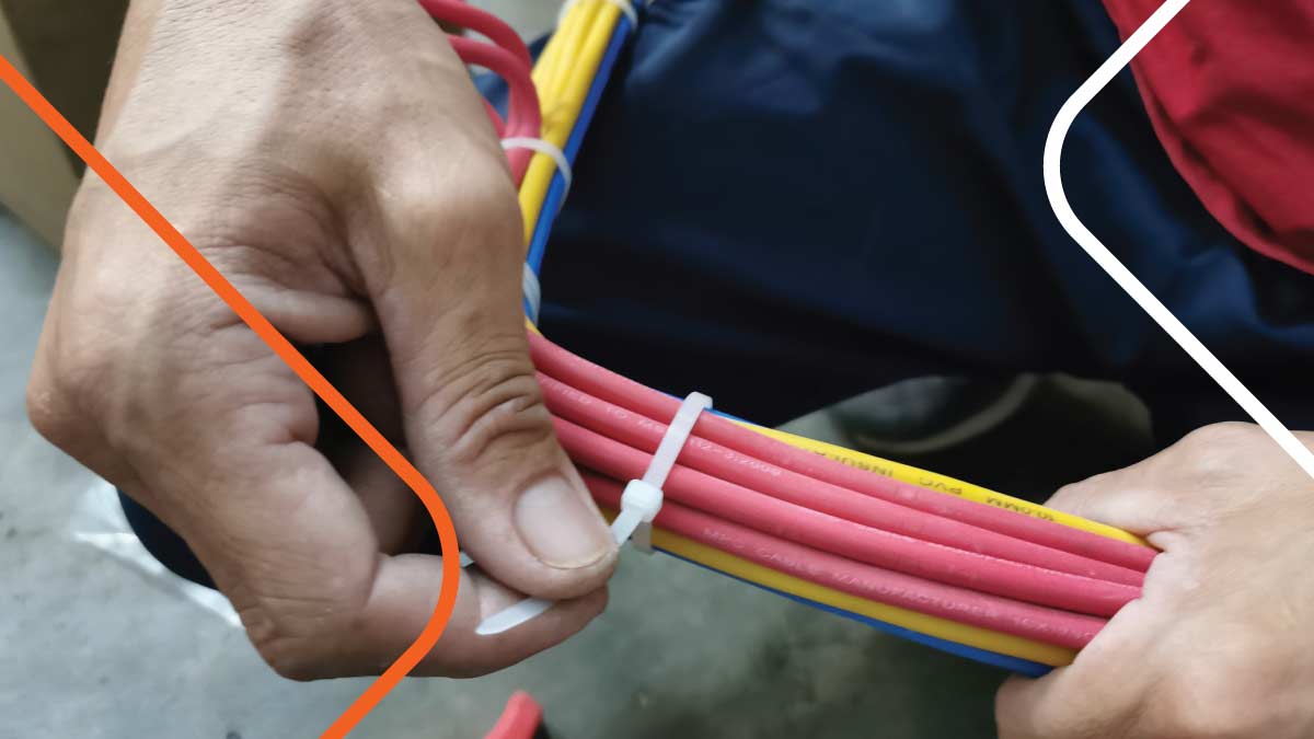 Close-up of technician hands tying up network cables.