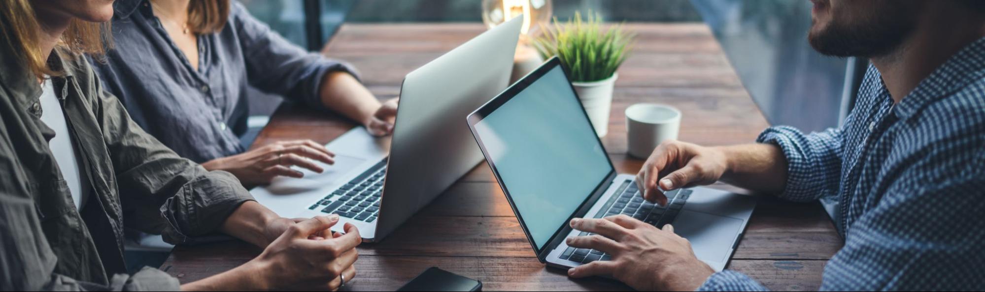 Faceless people sitting at a table with laptops