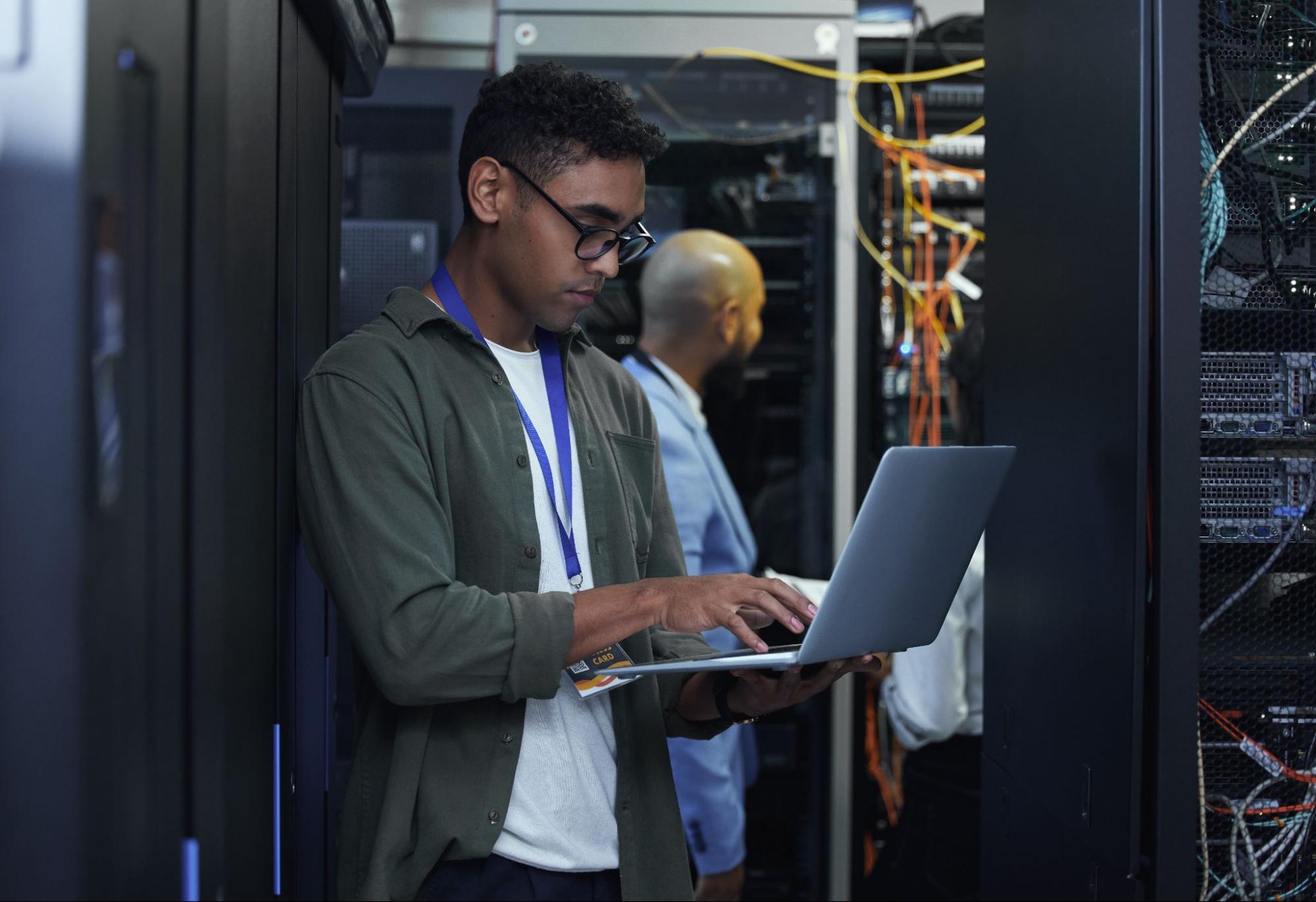 Man in a green shirt with a laptop working in the server room