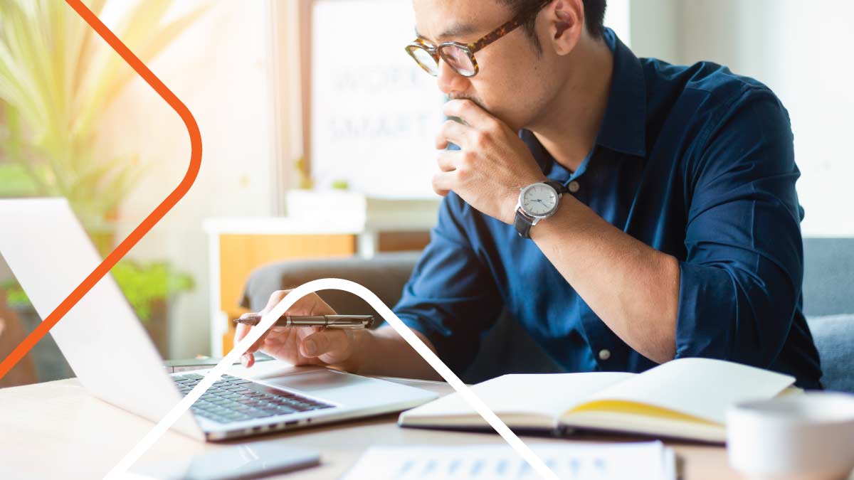 Man looking at laptop screen with documents on a desk