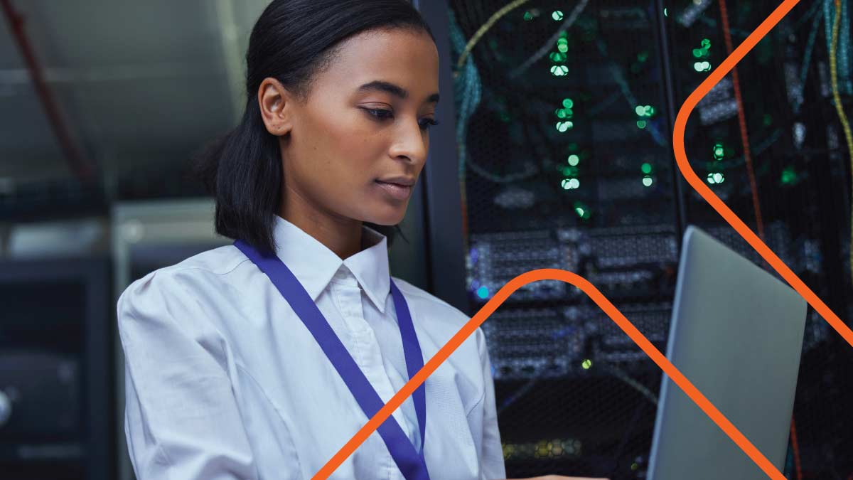 Woman with collared shirt working with laptop in server room