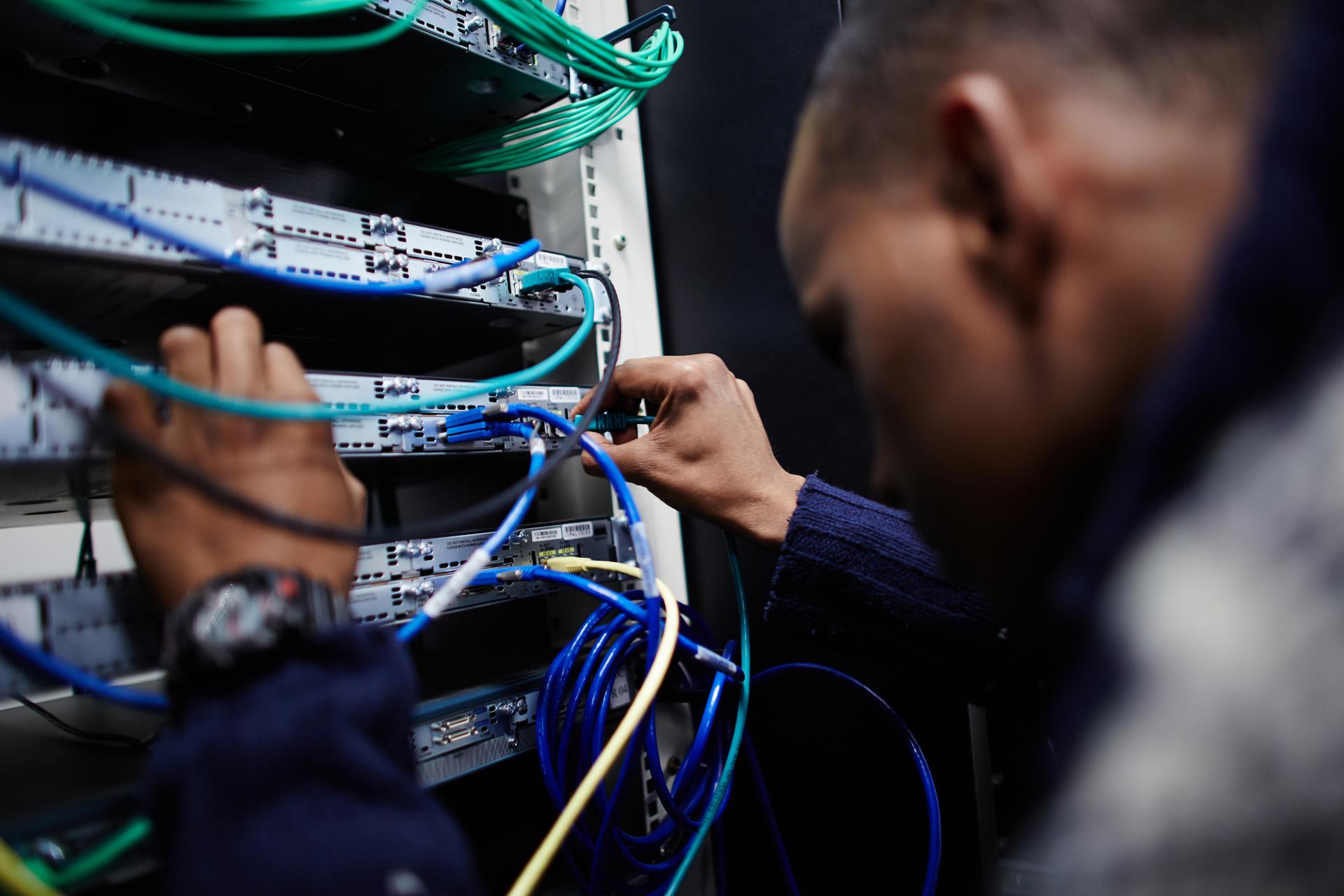 technician connecting cables in a network server room