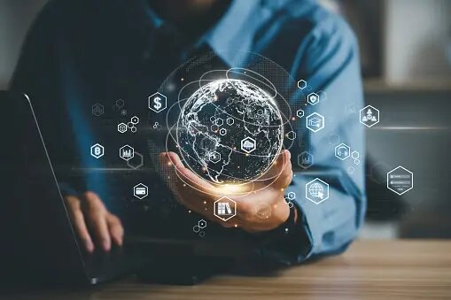 A person’s hands working on a computer and holding a holographic world map