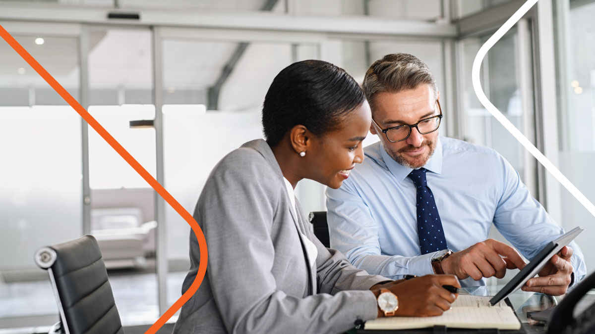 Man and woman having office meeting while looking at touchscreen tablet together