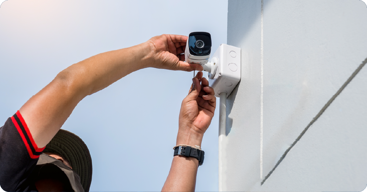 Man leaning up to work on a security camera